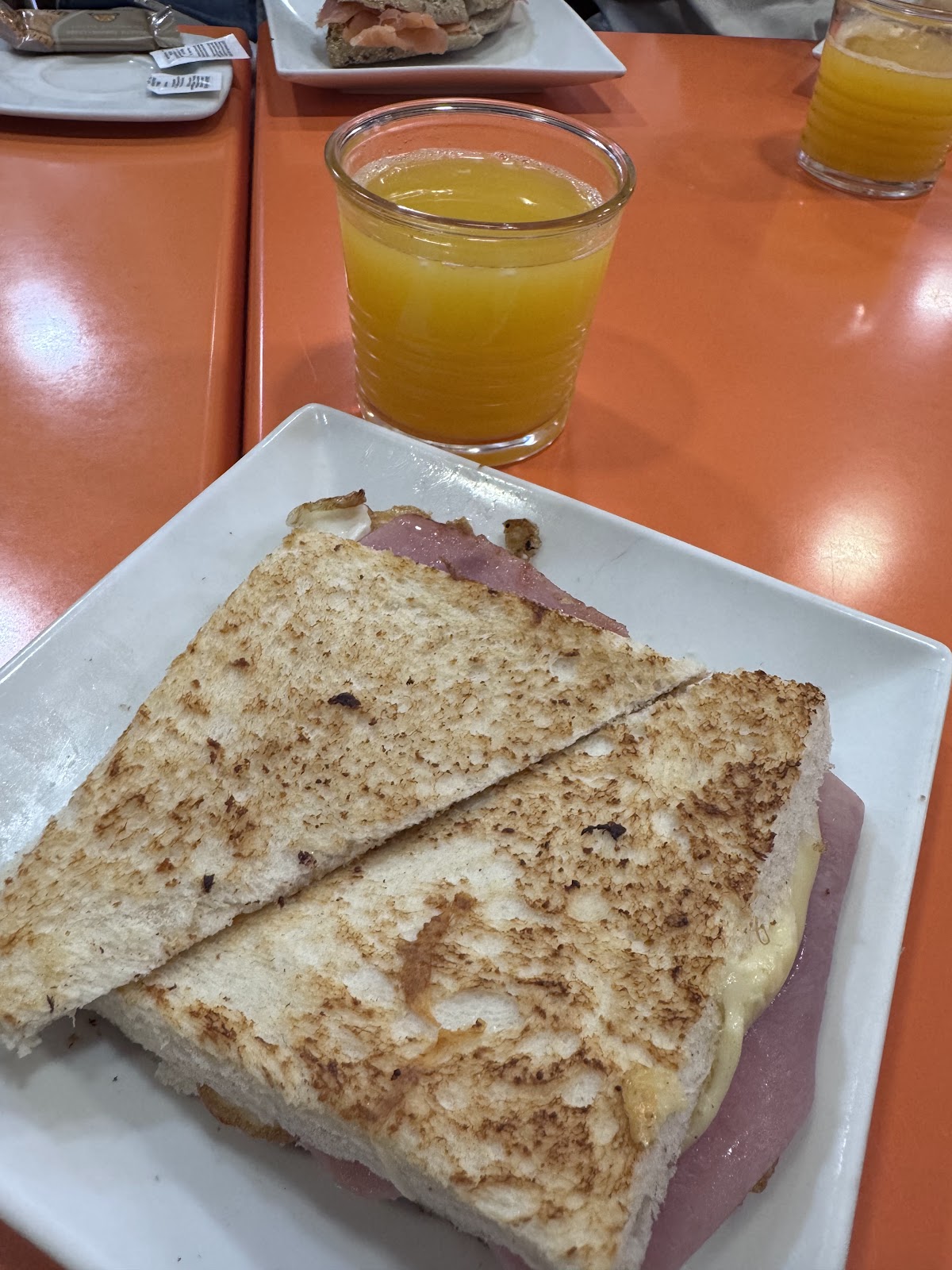 Sándwich mixto tostado acompañado de zumo de naranja.